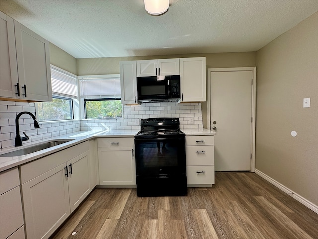 kitchen with sink, hardwood / wood-style flooring, decorative backsplash, white cabinetry, and black appliances