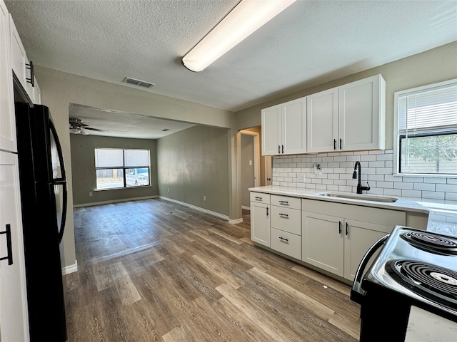 kitchen with hardwood / wood-style floors, sink, black appliances, and white cabinetry