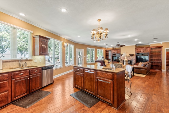 kitchen featuring sink, hardwood / wood-style flooring, light stone counters, decorative backsplash, and dishwasher