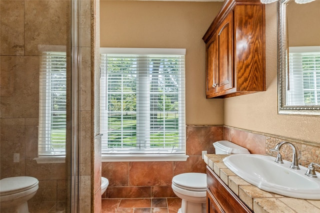 bathroom featuring toilet, vanity, and tile walls