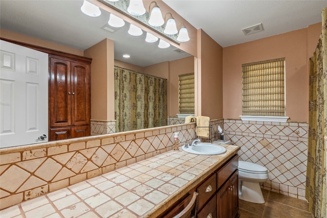 bathroom with tile patterned floors, tile walls, vanity, and toilet