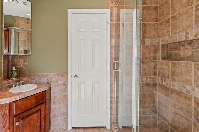 bathroom with tile walls, vanity, and walk in shower