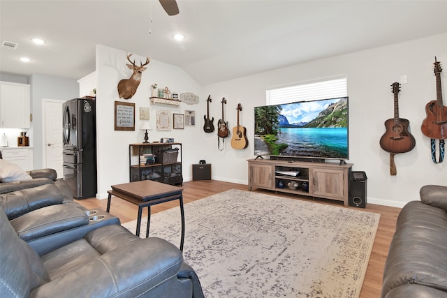 living room with ceiling fan, light wood-type flooring, and lofted ceiling