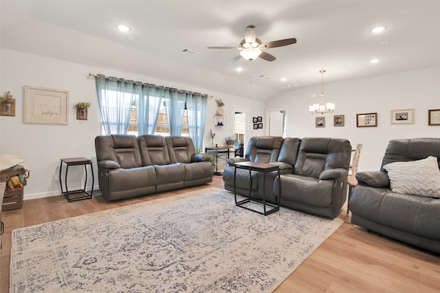 living room featuring vaulted ceiling, ceiling fan with notable chandelier, and wood-type flooring