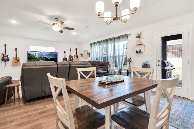 dining space with light wood-type flooring and ceiling fan with notable chandelier