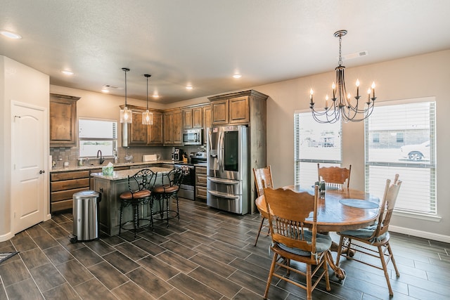 dining area with sink, dark wood-type flooring, and a notable chandelier