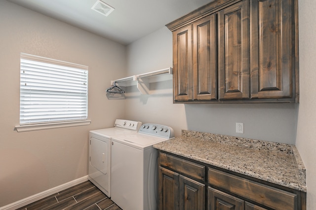 laundry area featuring washing machine and dryer, dark hardwood / wood-style flooring, and cabinets