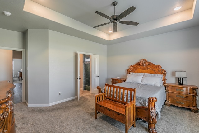 carpeted bedroom featuring a tray ceiling and ceiling fan