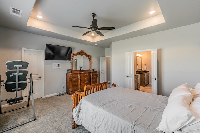 carpeted bedroom featuring connected bathroom, a raised ceiling, and ceiling fan