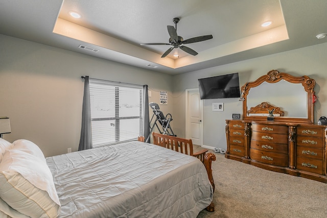 carpeted bedroom featuring a tray ceiling and ceiling fan