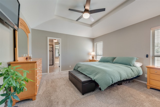 bedroom with ceiling fan, light carpet, connected bathroom, and a tray ceiling