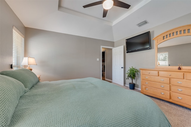 carpeted bedroom featuring ceiling fan and a raised ceiling