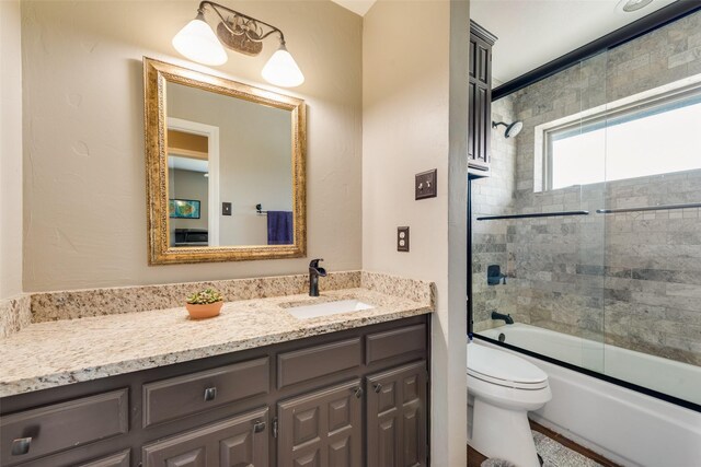 full bathroom with combined bath / shower with glass door, toilet, and vanity