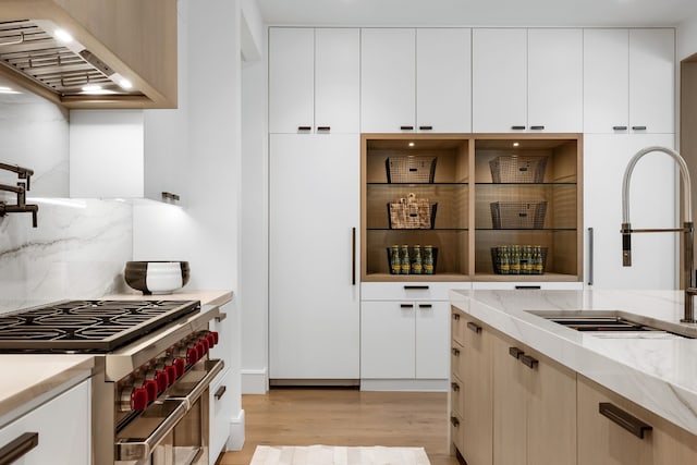 kitchen with light wood-type flooring, range with two ovens, custom range hood, and white cabinetry