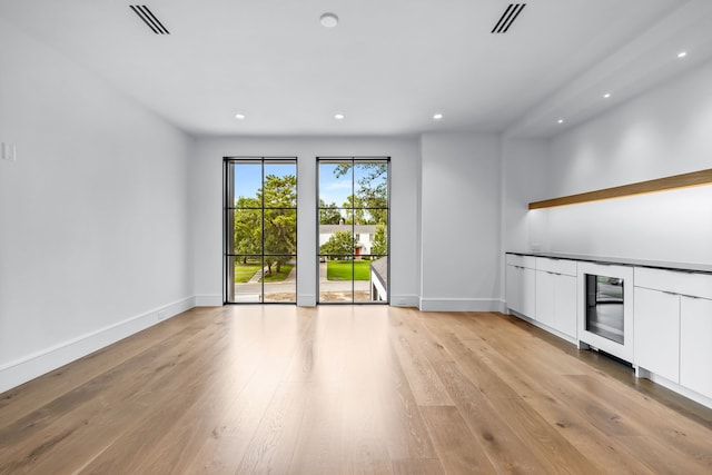 unfurnished living room with light wood-type flooring and wine cooler