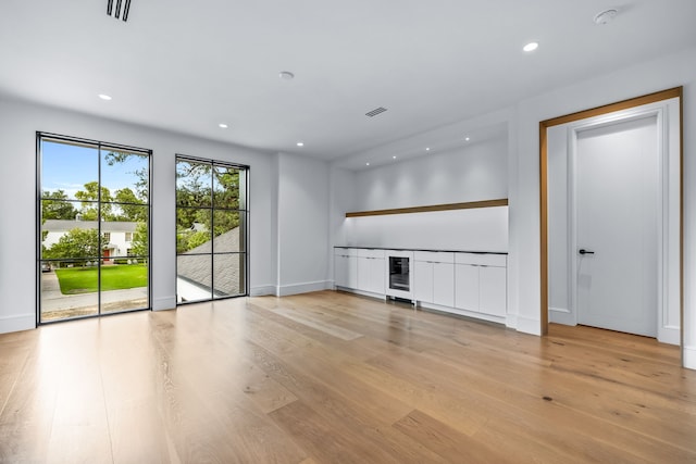 unfurnished living room with light wood-type flooring and beverage cooler