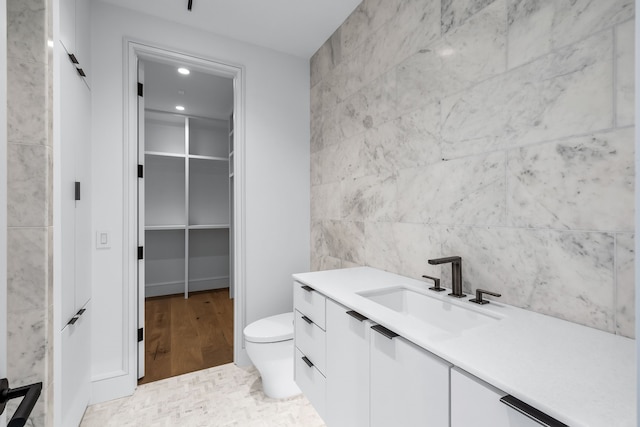 bathroom featuring toilet, tile walls, tile patterned flooring, and vanity