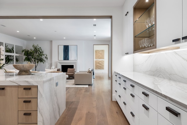 kitchen featuring light hardwood / wood-style flooring, white cabinetry, and light stone counters