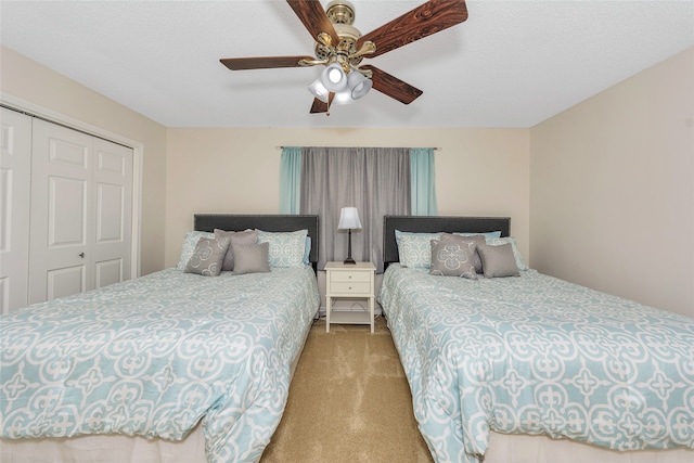 bedroom with ceiling fan, a closet, light carpet, and a textured ceiling