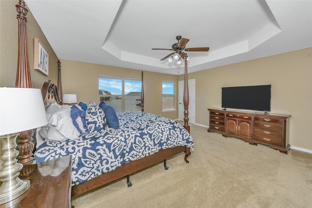 bedroom featuring ceiling fan, a raised ceiling, and light carpet