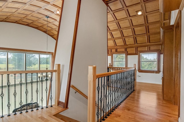 hall featuring baseboards, vaulted ceiling, wood finished floors, and an upstairs landing