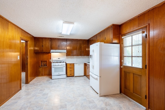 kitchen featuring a textured ceiling, wood walls, white appliances, and light tile patterned floors