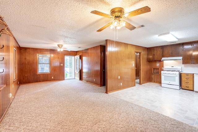 kitchen featuring ceiling fan, light carpet, wooden walls, and white appliances