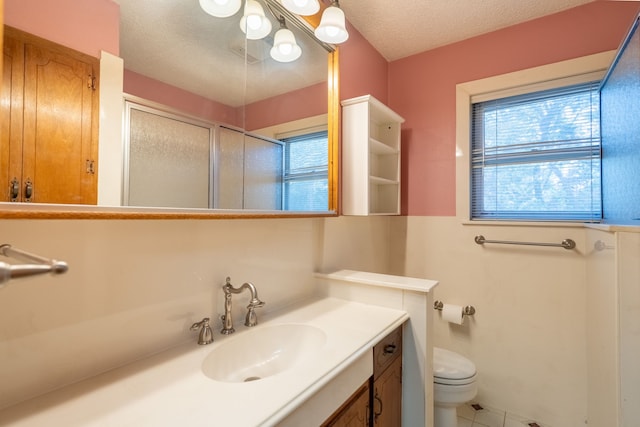 bathroom featuring vanity, tile patterned flooring, toilet, a textured ceiling, and a stall shower