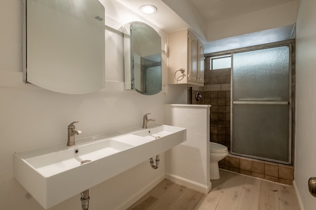 bathroom with hardwood / wood-style floors, toilet, and an enclosed shower