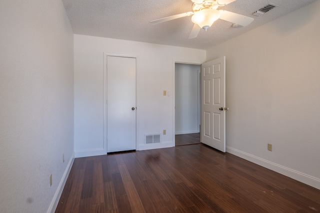 unfurnished bedroom with dark hardwood / wood-style flooring, a closet, a textured ceiling, and ceiling fan