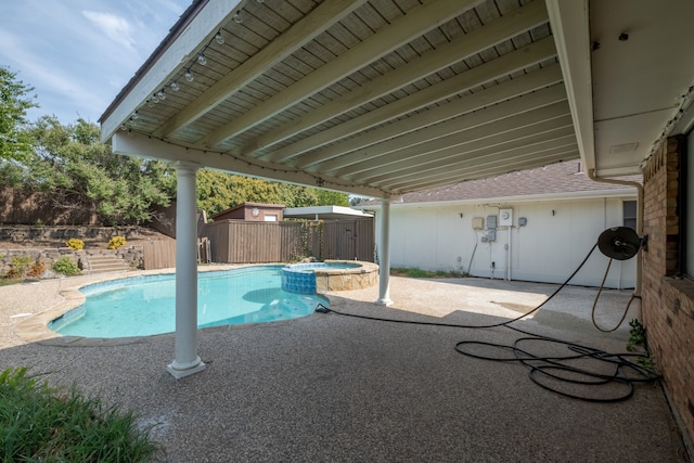 view of pool featuring an in ground hot tub, a patio, and a shed