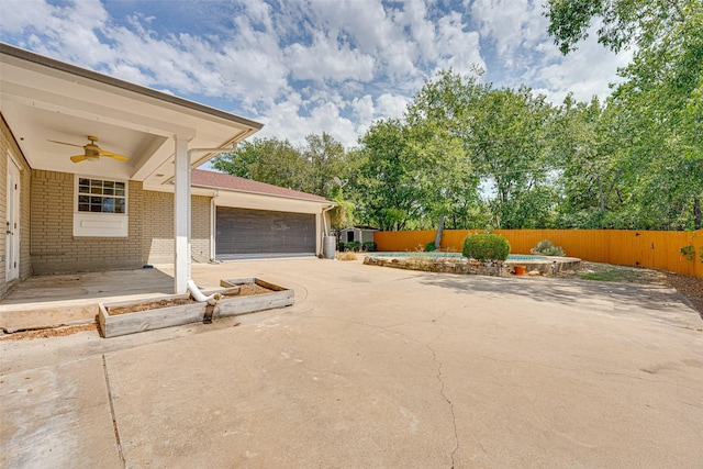 view of patio / terrace with ceiling fan, a garage, and a pool