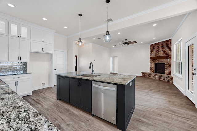 kitchen featuring stainless steel dishwasher, light hardwood / wood-style flooring, white cabinetry, sink, and a fireplace