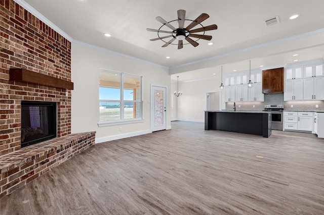 kitchen featuring stainless steel electric stove, decorative light fixtures, a fireplace, hardwood / wood-style flooring, and decorative backsplash