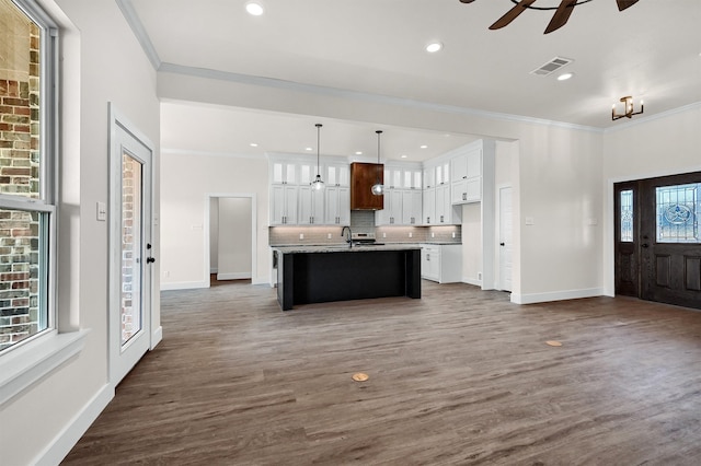 kitchen with ceiling fan, backsplash, dark hardwood / wood-style flooring, hanging light fixtures, and a center island with sink