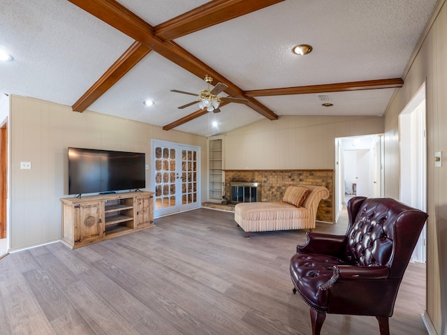 living room with french doors, a textured ceiling, ceiling fan, lofted ceiling with beams, and light hardwood / wood-style flooring