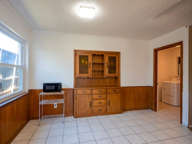 unfurnished office with wooden walls, a textured ceiling, washer / dryer, and light tile patterned floors