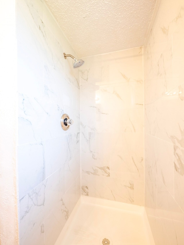 bathroom featuring a textured ceiling and a tile shower