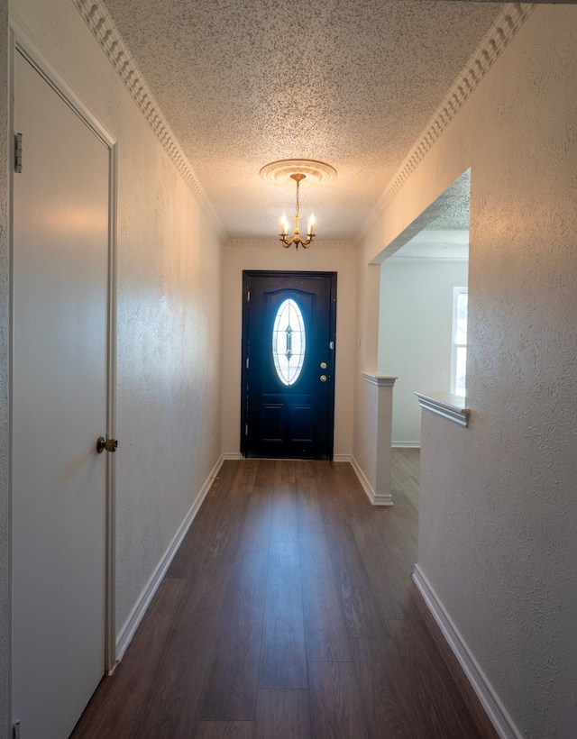 doorway to outside featuring an inviting chandelier, crown molding, a textured ceiling, and dark hardwood / wood-style flooring