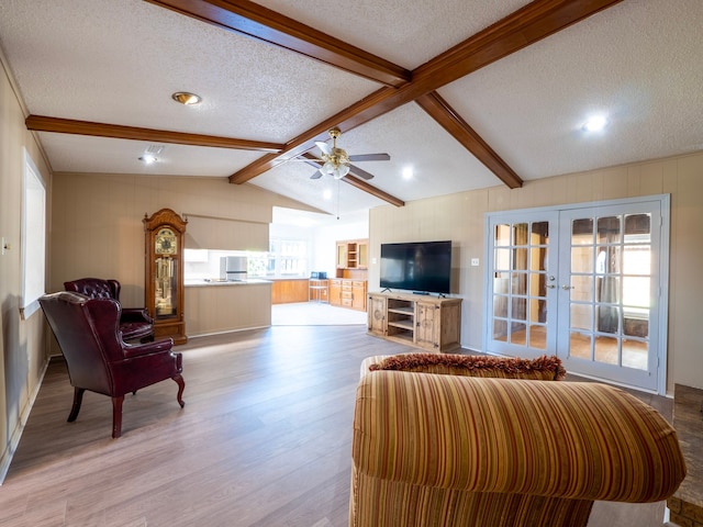 living room featuring ceiling fan, a textured ceiling, light hardwood / wood-style flooring, vaulted ceiling with beams, and french doors