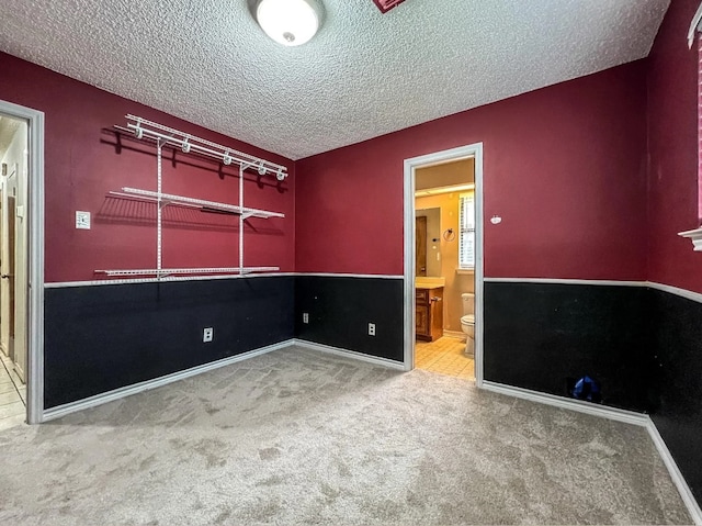 unfurnished room with carpet, baseboards, and a textured ceiling