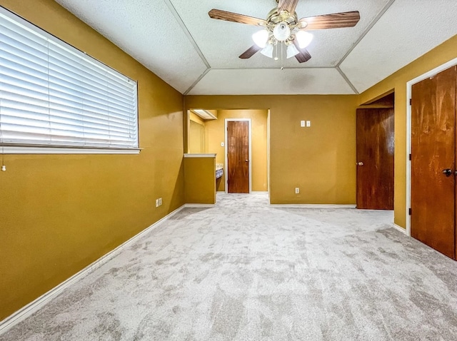 unfurnished bedroom with lofted ceiling, a textured ceiling, carpet, and baseboards
