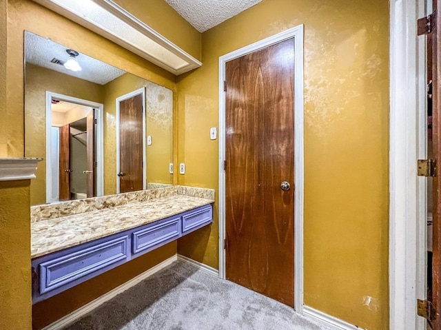 bathroom with baseboards, a textured ceiling, and vanity