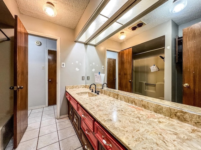 bathroom with a textured ceiling, tile patterned flooring, a skylight, vanity, and walk in shower