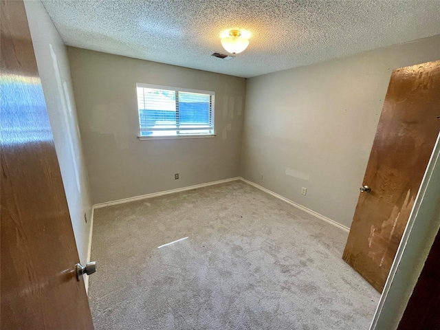 unfurnished bedroom with carpet, a textured ceiling, visible vents, and baseboards