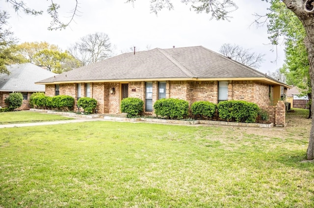 ranch-style house featuring roof with shingles, a front lawn, and brick siding