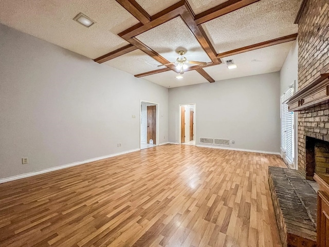 unfurnished living room with light wood-type flooring, ceiling fan, a textured ceiling, and a fireplace