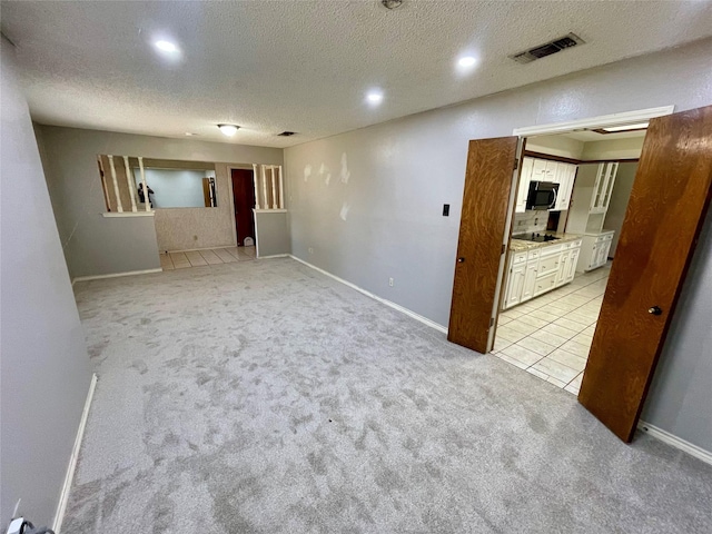 empty room featuring light colored carpet, visible vents, and a textured ceiling