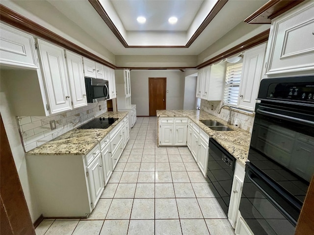kitchen with a tray ceiling, white cabinets, a sink, and black appliances