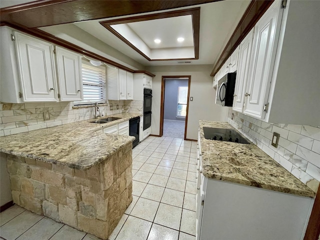 kitchen featuring a tray ceiling, white cabinetry, a sink, and black appliances